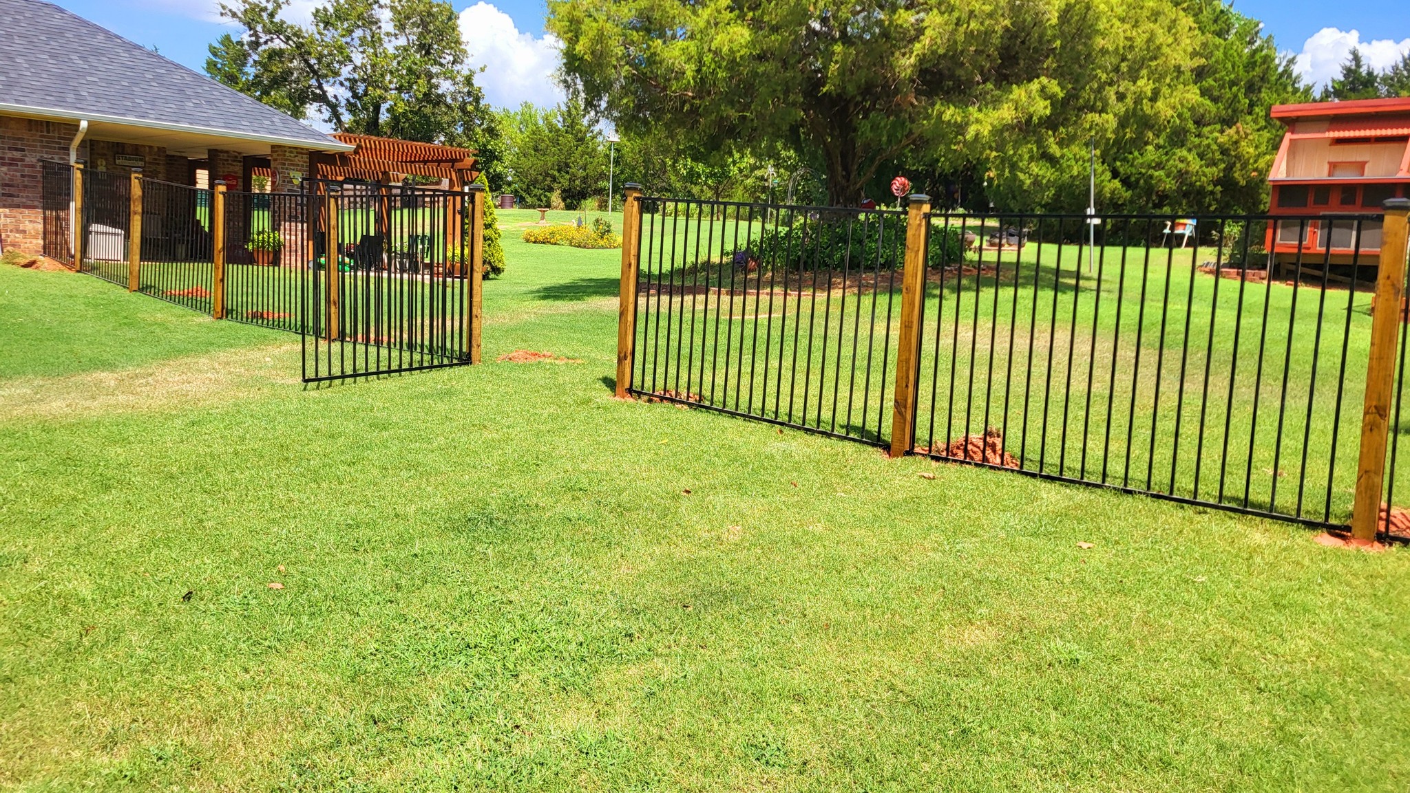 Iron fence panels with wood posts and gate installation by A&R Fencing and Landscaping