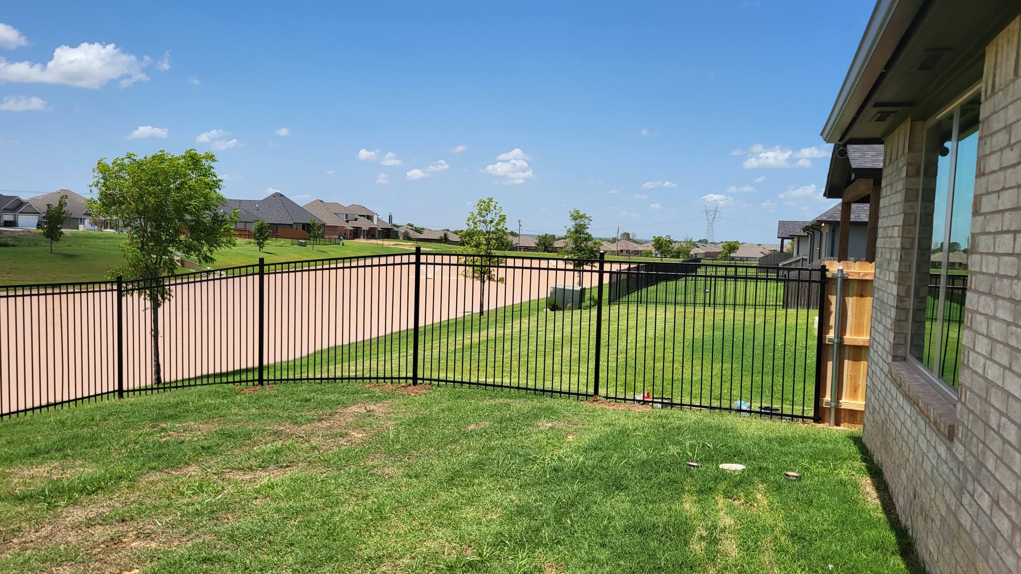 Black ornamental iron fence installed in a residential backyard by A&R Fencing and Landscaping